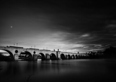 Fotografía del llamado Puente Viejo o puente de Palmas en Badajoz con la luna sobre él.